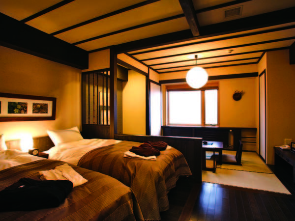 ベッドと畳空間が、民芸調の木調でまとめられた和洋室/例