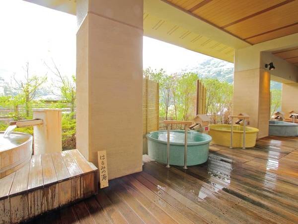 【「清流の湯」露天風呂】木目が美しいウッドテラスに様々なタイプの浴槽を備える