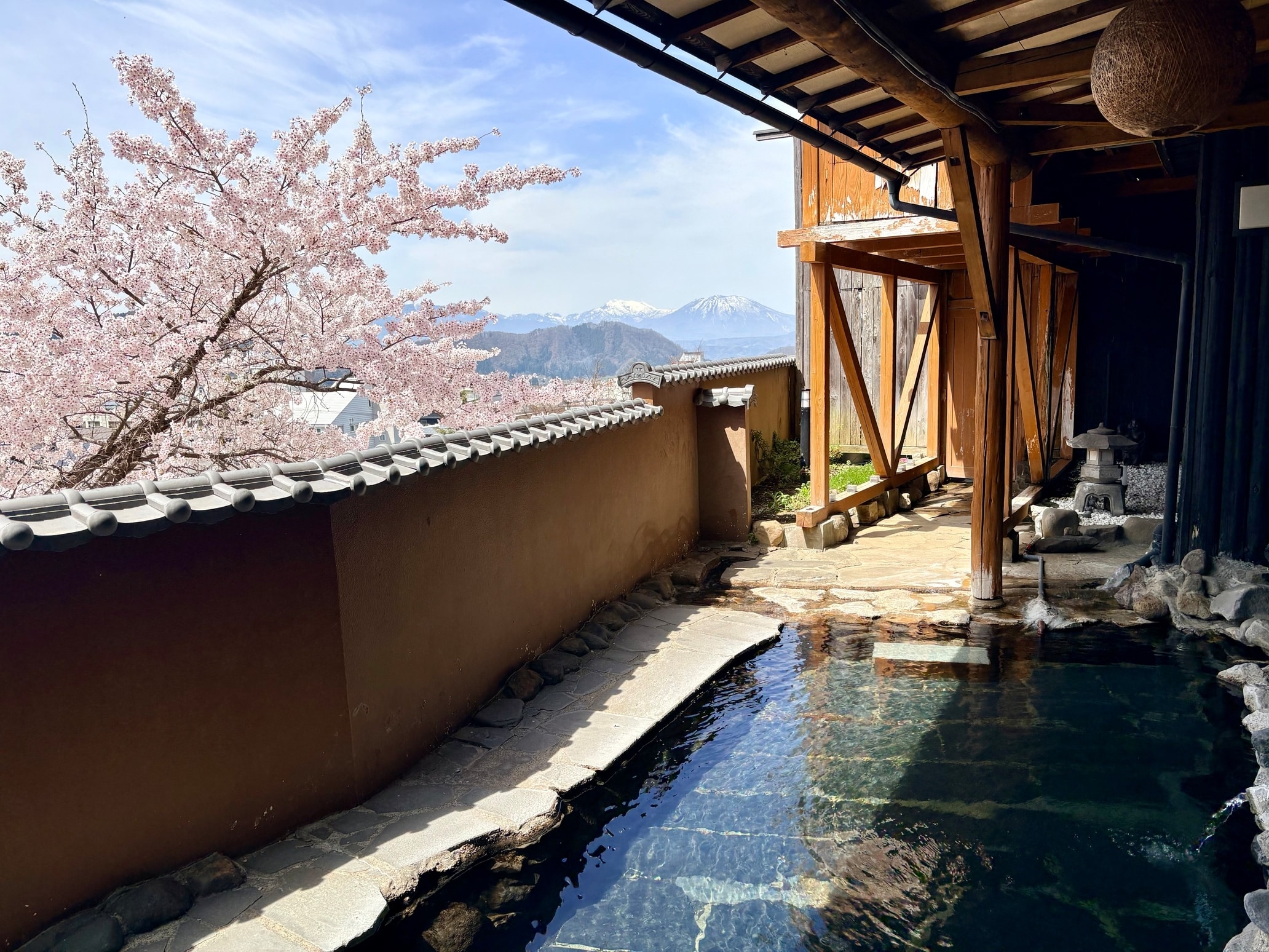 【「あやめの湯」岩露天風呂】春はブルーの山脈と桜で花見風呂