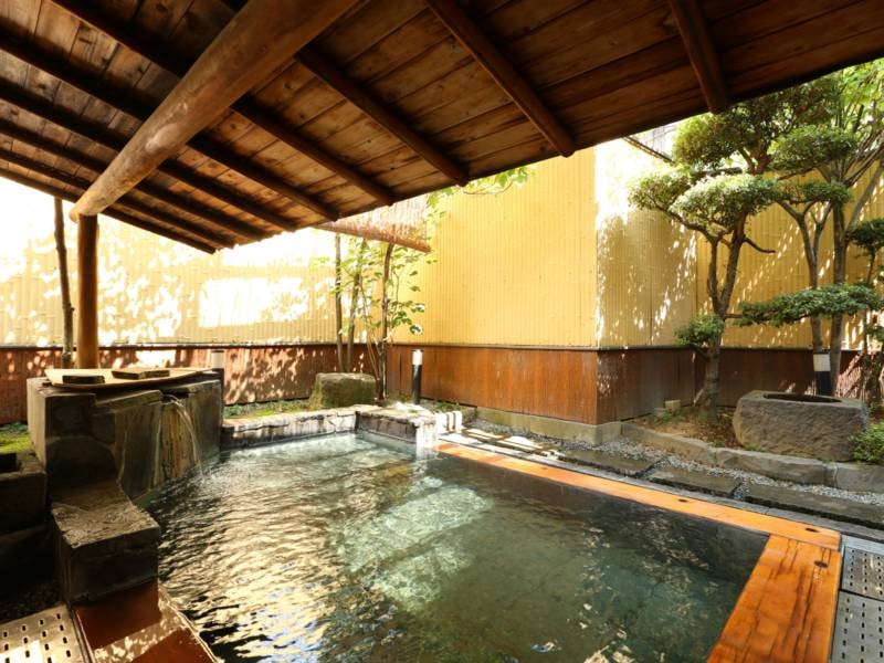 【1階露天風呂(男性露天風呂)】伊豆石と檜で造られた浴槽で源泉かけ流しの温泉を堪能