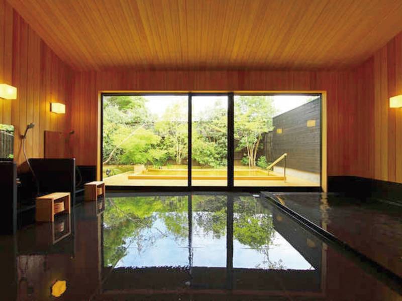 【大浴場/湯処「風花」】黒の浴槽と檜のコントラストが美しい空間