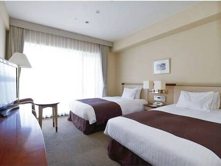 【ツインルーム/例】シモンズ社製ベッドを完備。窓から駅前広場を眺められる